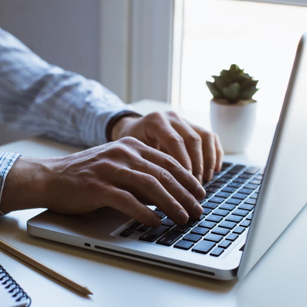 Illustrative photo of hands typing on a laptop at a desk